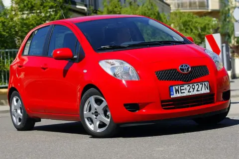 Czerwony Toyota Yaris 2008 z polskimi tablicami rejestracyjnymi WE 2927N jedzie po ulicy.