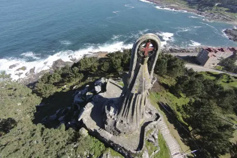 La Virgen de la Roca, una imponente estatua de piedra, vigila el mar azul desde un acantilado verde.