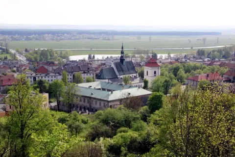 Widok na Pińczów z górującym kościołem i klasztorem. W oddali pola i lasy. Odkryj pińczów atrakcje!