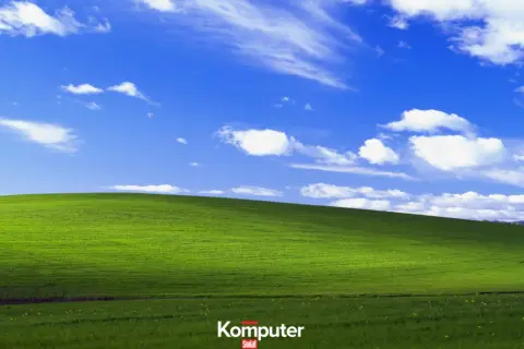 Zielone wzgórze pod błękitnym niebem z białymi chmurami, ikoniczny krajobraz z **Windows XP**.
