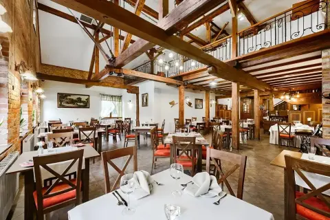 Przytulna restauracja w hotelu Młyn Elbląg. Drewniane belki, ceglane ściany i eleganckie stoły tworzą niepowtarzalny klimat.