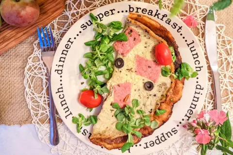 Omlet z szynką, pomidorkami i rukolą na talerzu z napisami "breakfast", "lunch", "dinner", "supper".