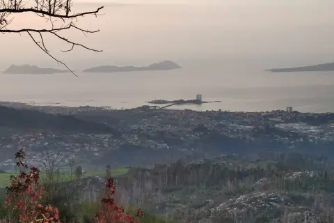 Vista panorámica desde el monte alba: islas Cíes, ciudad costera y bosques.