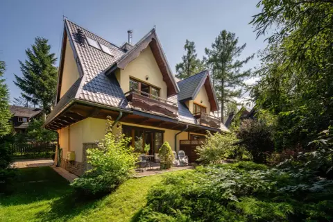 Urokliwy pensjonat w Zakopanem, z widokiem na Giewont. Dom otoczony zielenią, z drewnianymi balkonami i tarasem.