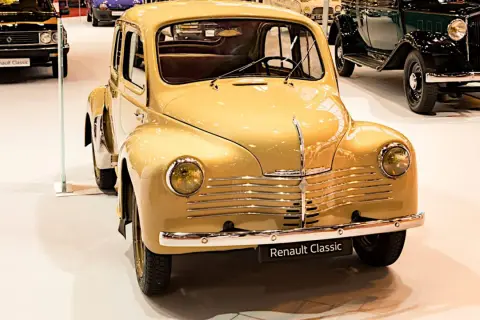 En gul, klassisk Renault 4CV står i förgrunden, en av många gamla Renault modeller på utställningen.