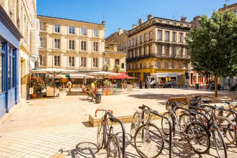 Sonniger Platz in Bordeaux mit Cafés, Fahrrädern und charmanten Gebäuden – ein echter bordeaux geheimtipp.