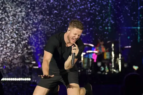 Imagine Dragons wokalista Dan Reynolds śpiewa z pasją na scenie, otoczony konfetti.