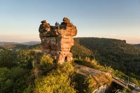 Dwie osoby stoją na szczycie skalnej wieży, podziwiając malownicze góry w zachodnich Niemczech.