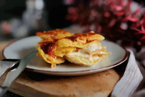 Ein Stück cremiges Kartoffelgratin mit goldbrauner Kruste auf einem Teller, bereit zum Genießen. Dieses Kartoffelgratin Rezept ist ein Genuss!