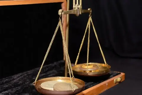 Złota waga szalkowa z monetami na jednej szalce. Czy to jest ile to jedna uncja?