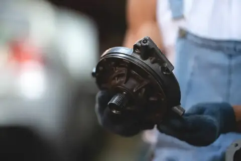 Mechanik pokazuje element pompy wspomagającej hamulce, wyjaśniając, jak działa serwo hamulcowe.