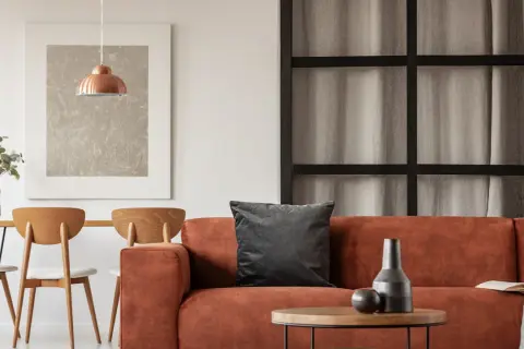 Gemütliche Wohnung inspo: Orange Couch, Holztisch mit Stühlen und ein kupferfarbener Lampenschirm.