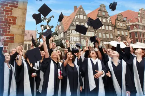 Absolventen der Apollon Hochschule werfen ihre Hüte in die Luft. Tolle Erfahrungen und ein erfolgreicher Abschluss!