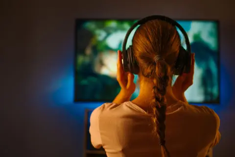 Dziewczyna w słuchawkach zanurzona w świecie filmu, gdzie muzyka buduje nastrój.