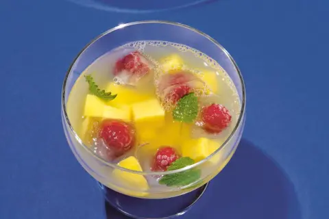 Erfrischende alkoholfreie Bowle mit Mango, Himbeeren und Minze in Eiswürfeln.