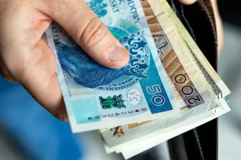 Dłoń trzyma polskie banknoty. Wkrótce jawność wynagrodzeń 2026, więc warto wiedzieć, ile zarabiamy.