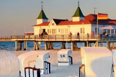 Spacerem z Świnoujścia do Ahlbecku, przez molo z restauracją i plażowe kosze.