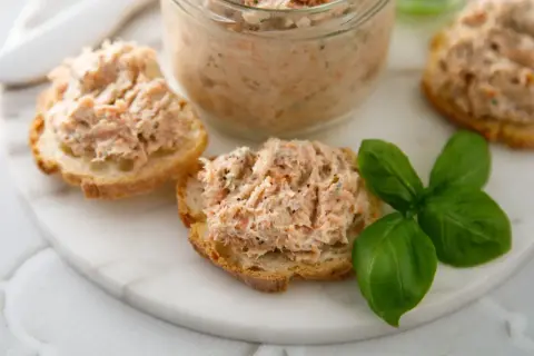 Pyszna pasta rybna na chrupiących grzankach, ozdobiona świeżą bazylią. Idealna na szybką przekąskę.