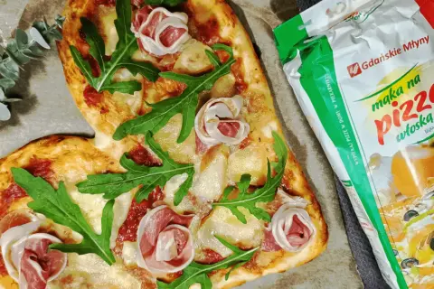 Serce z pizzy z rukolą i szynką, obok mąka do pizzy. Idealne do pieczenia pizzy w piekarniku.