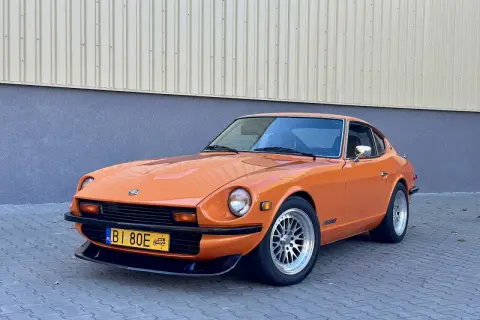 Pomarańczowy Datsun 280Z z lat 70. na tle budynku. Klasyk motoryzacji gotowy na przejażdżkę.