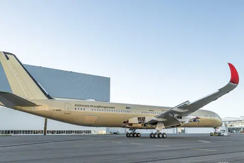 Złoty samolot Airbus z napisem #Ultimate #LongRangeLeader, gotowy do najdłuższego lotu samolotem.