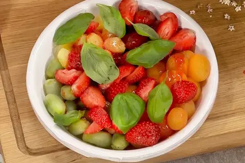 En fräsch sallad med jordgubbar, gröna vindruvor och körsbärstomater, toppad med basilika. Perfekt sommarbuffé!