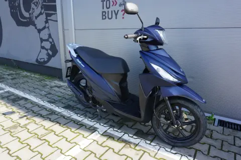 Elegancki, granatowy skuter Suzuki Address 110 zaparkowany na kostce brukowej.