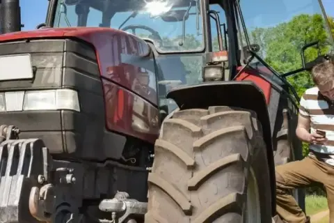Zwei Männer besprechen den Einsatz eines Traktors. Der jüngere schaut aufs Handy, der ältere hält eine Mappe. Ein guter Verdienst als Fachkraft Agrarservice ist wichtig.