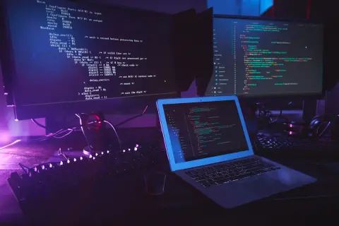 Code informatique sur plusieurs écrans, avec un clavier et un ordinateur portable. Le code Python utilise la méthode `strip` pour nettoyer les chaînes.