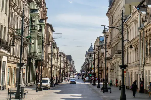 Belebte Straße in der lodz altstadt mit historischen Gebäuden, Autos und Fußgängern.