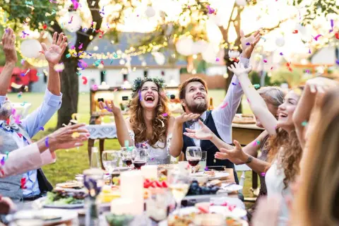 Joyeuse animation anniversaire de mariage en plein air, avec des confettis colorés pleuvant sur des invités souriants et un couple rayonnant.