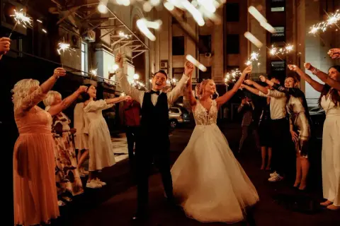 Un couple de mariés rayonnant, entouré d'invités tenant des feux de Bengale, pour un thème mariage étoile scintillant.