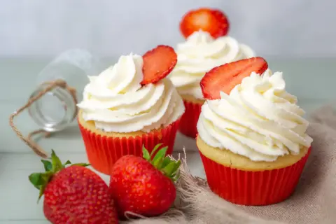 Erdbeer Cupcakes mit weißer Creme und frischen Erdbeeren, dekoriert mit Erdbeerscheiben.