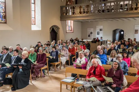 Menschen sitzen in einer Kirche und singen. Dies ist ein Beispiel dafür, was ist eine Freikirche: eine Gemeinschaft, die sich selbst organisiert.
