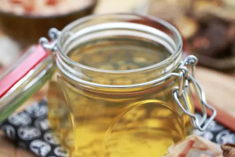 Goldgelbe Flüssigkeit in einem Bügelglas, die anzeigt, was ist Dashi.