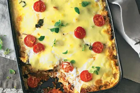 Herzhafte low carb Lasagne mit geschmolzenem Käse und Kirschtomaten, garniert mit frischen Kräutern.