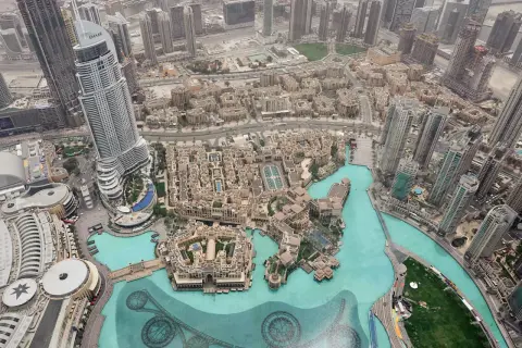 Widok z góry na Dubaj, z najwyższym budynkiem w Dubaju, Emaar, dominującym nad miastem i otoczonym przez turkusową wodę.