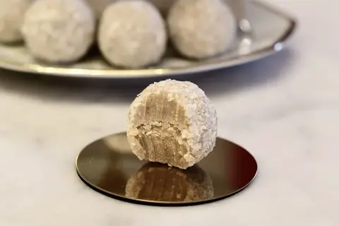 En bit tagen ur en av de fluffiga vita chokladbollarna, som är rullade i kokosflingor.