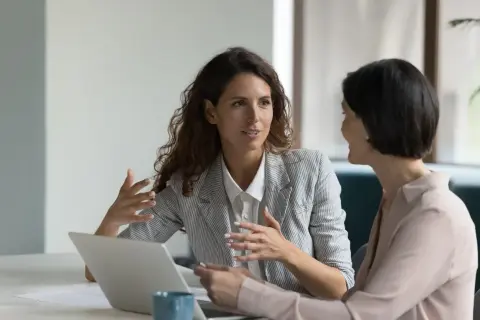 Due donne discutono di un mutuo senza ipoteca, con un laptop aperto sul tavolo.