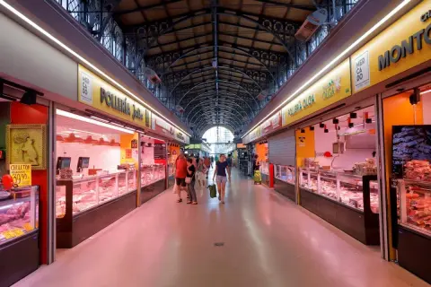 Pasillo del mercado San Miguel Zaragoza, con puestos de carne y pollo, gente comprando.