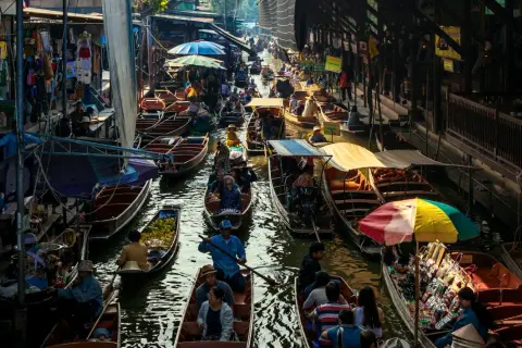 Livligt marknadsliv i Bangkok med båtar fyllda med varor och människor som navigerar på kanalen.