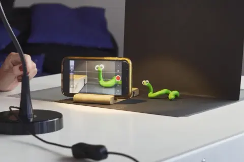Tworzenie zielonych robaczków do animacji poklatkowej. Telefon nagrywa, ręka reguluje lampę.