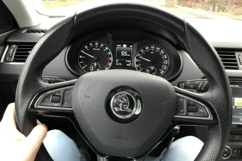Blick auf das Lenkrad eines Autos mit Tachometeranzeige 55 km/h. Die Spurstange einstellen ist hier nicht direkt sichtbar, aber die Fahrt geht weiter.