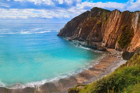 Aguas turquesas bañan la **cascada playa del Silencio**, rodeada de imponentes acantilados ocres y vegetación exuberante.