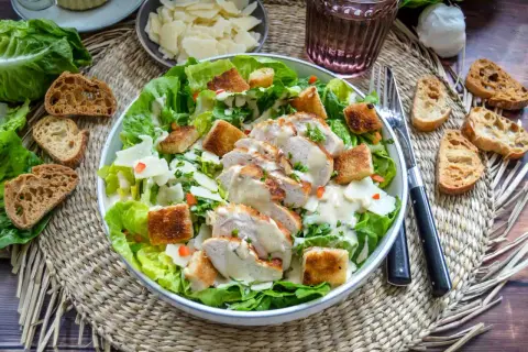 Ein köstlicher Cesar Salat mit gegrilltem Hähnchen, Croutons und cremigem Dressing. Dazu passen geröstete Brotscheiben.