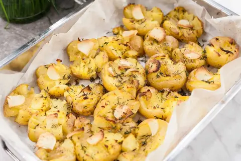Ugnsbakade, krossade potatisar med vitlök och örter i en ugnsform. Perfekt som tillbehör till en god middag.