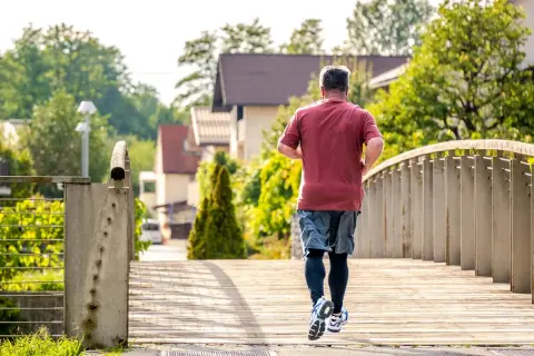 Un homme court sur un pont en bois, profitant du soleil matinal. C'est le meilleur moment pour courir, avec l'air frais et la nature verdoyante.