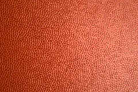 Texture d'un ballon de basket orange. Pour savoir si c'est du vrai cuir, observez la régularité des alvéoles.