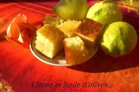 Gâteau au citron et à l'huile d'olive, une recette gâteau simple et délicieuse. Des parts de gâteau moelleux côtoient des citrons frais et une rose orangée sur un fond rouge.