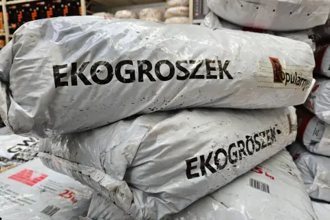 Stos worków z ekogroszkiem, widoczne napisy "EKOGROSZEK" i "Popularny".